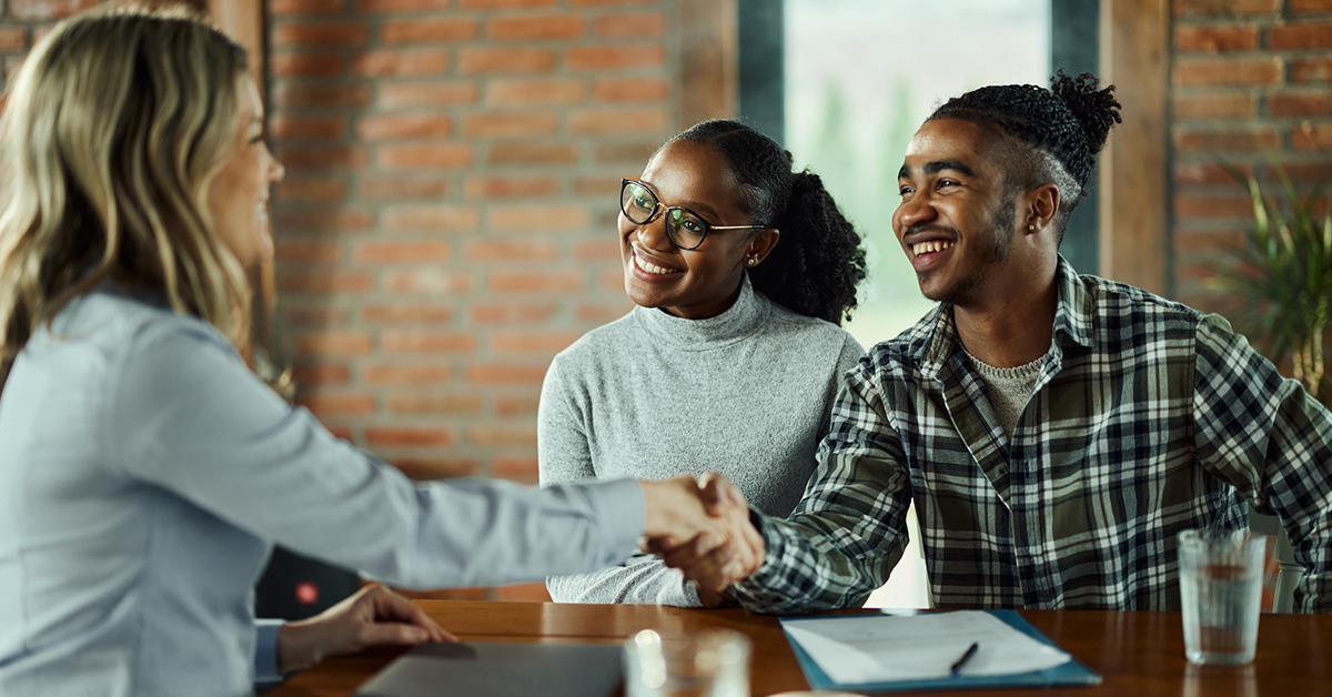 Happy real estate agent came to a successful agreement with a couple during a meeting in the office.